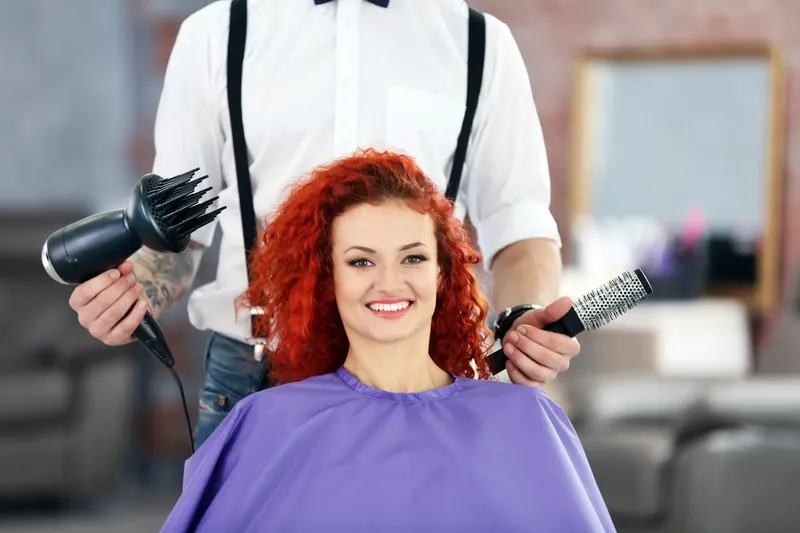 Stylist drying a client's freshly coloured copper hair