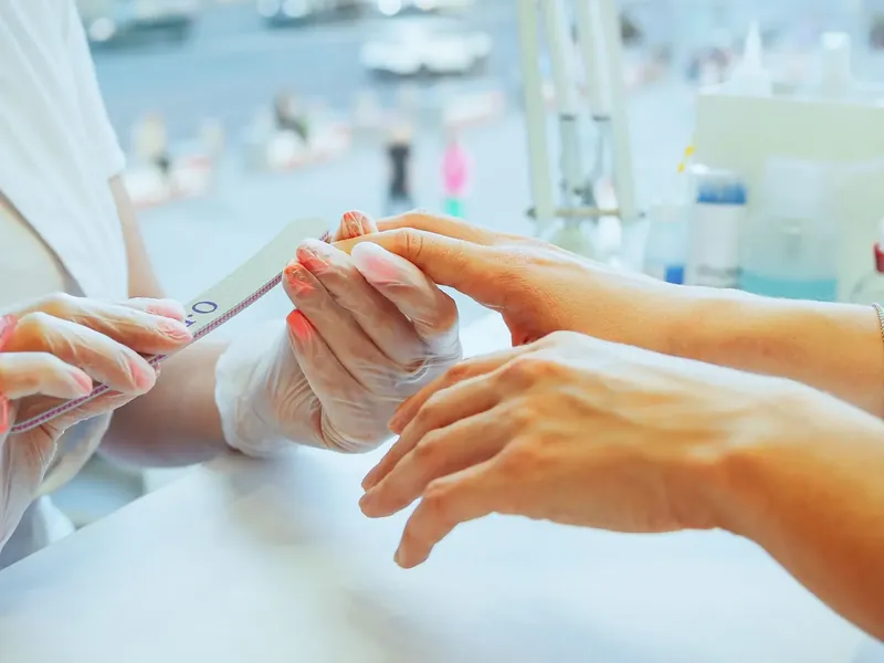 Nail technician in gloves filing a client's nails